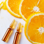Vitamin C serum ampoules with orange slices on marble