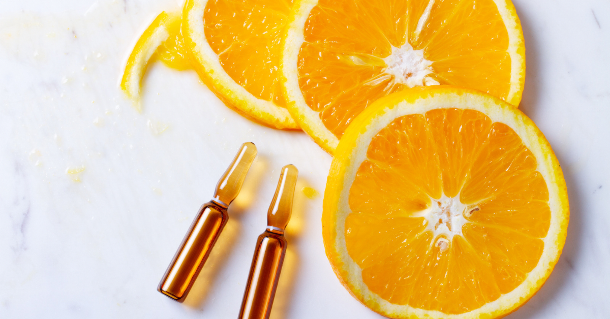 Vitamin C serum ampoules with orange slices on marble